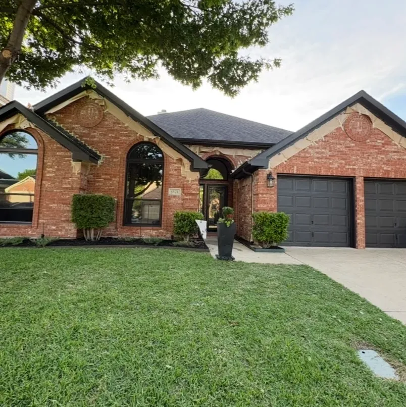 Completed exterior house painting project with freshly painted dark trim and garage doors in McKinney, TX