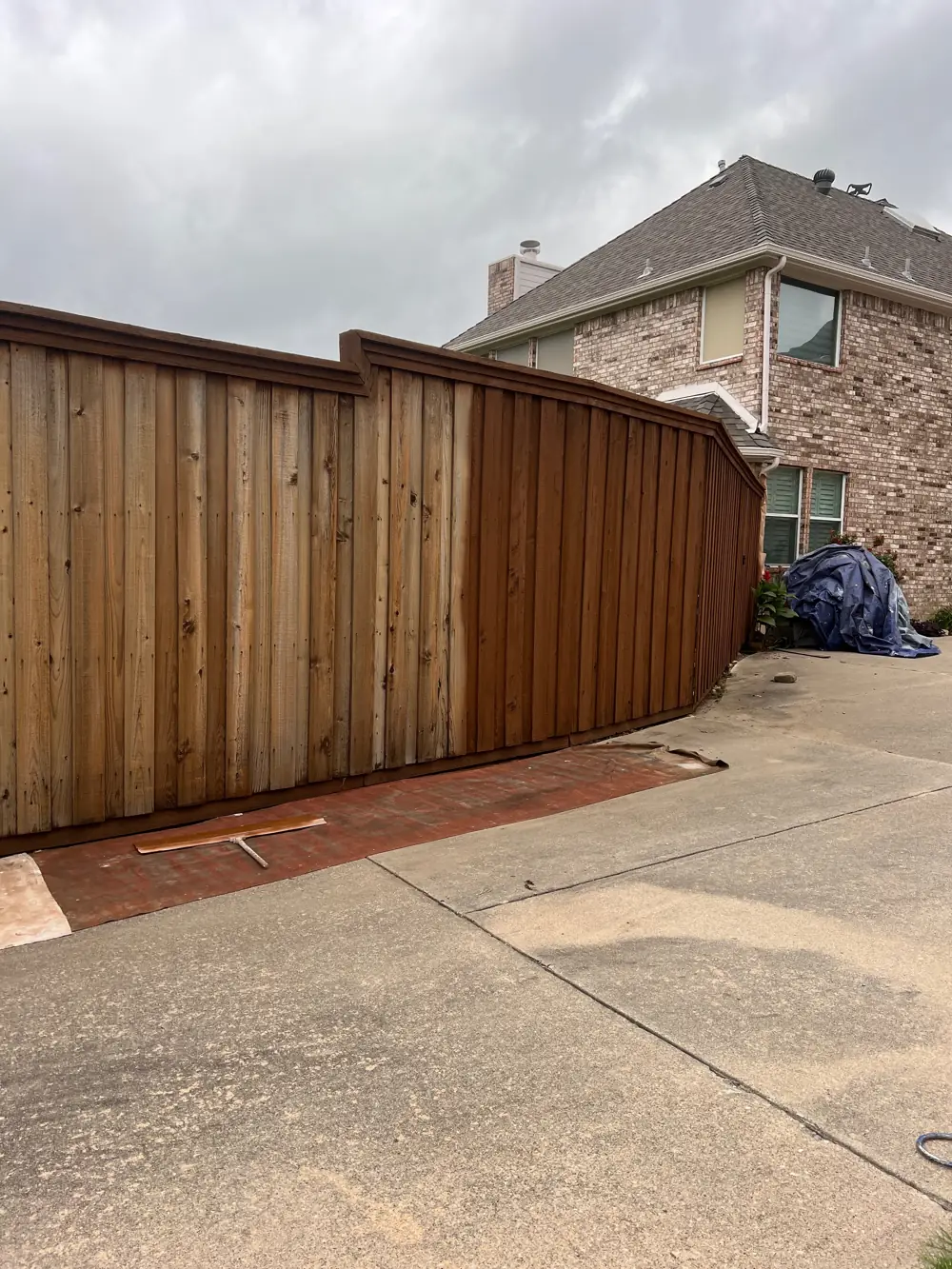 Before and after fence staining in McKinney, TX — raw gray cedar next to freshly stained boards