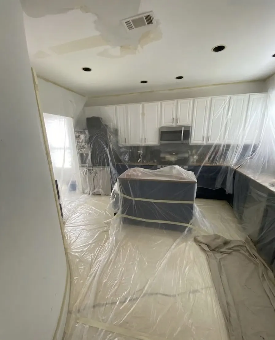Kitchen ceiling drywall repair with cabinets and countertops fully masked off in McKinney, TX