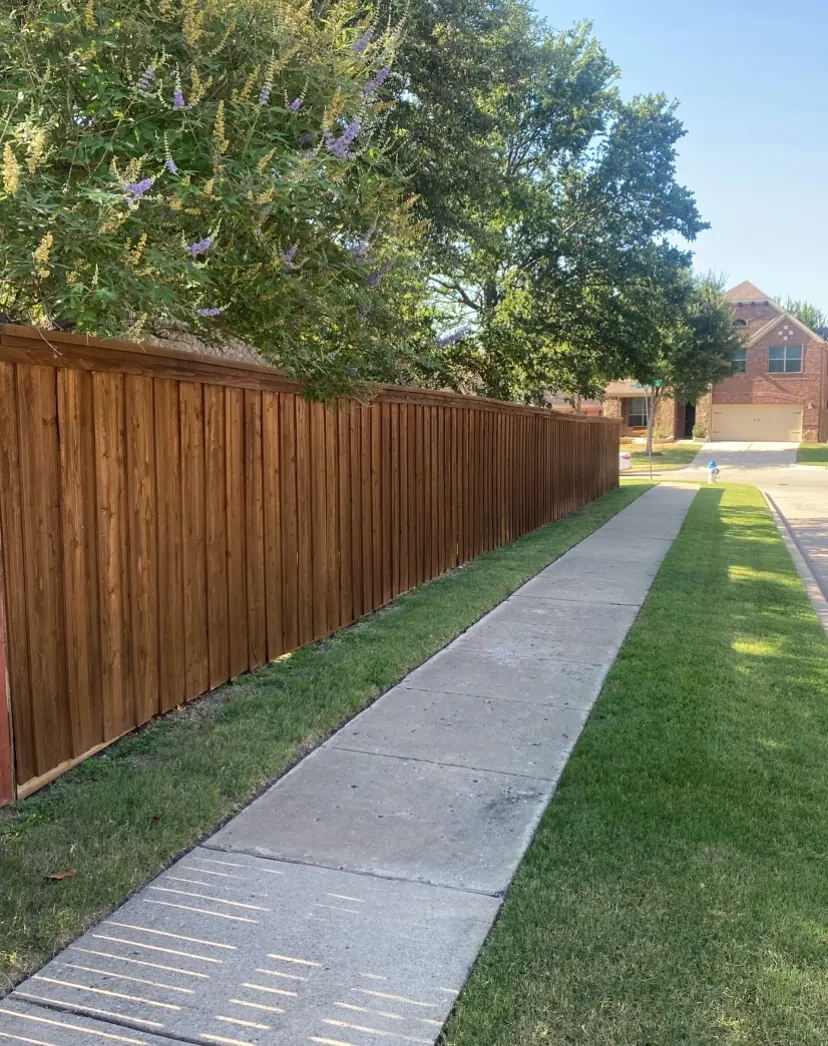 Long stained cedar fence run along a sidewalk in McKinney, TX