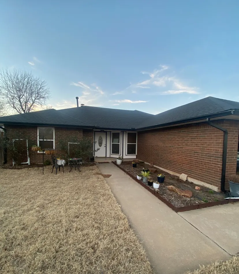 Brick home with new dark seamless gutters and downspouts installed in McKinney, TX