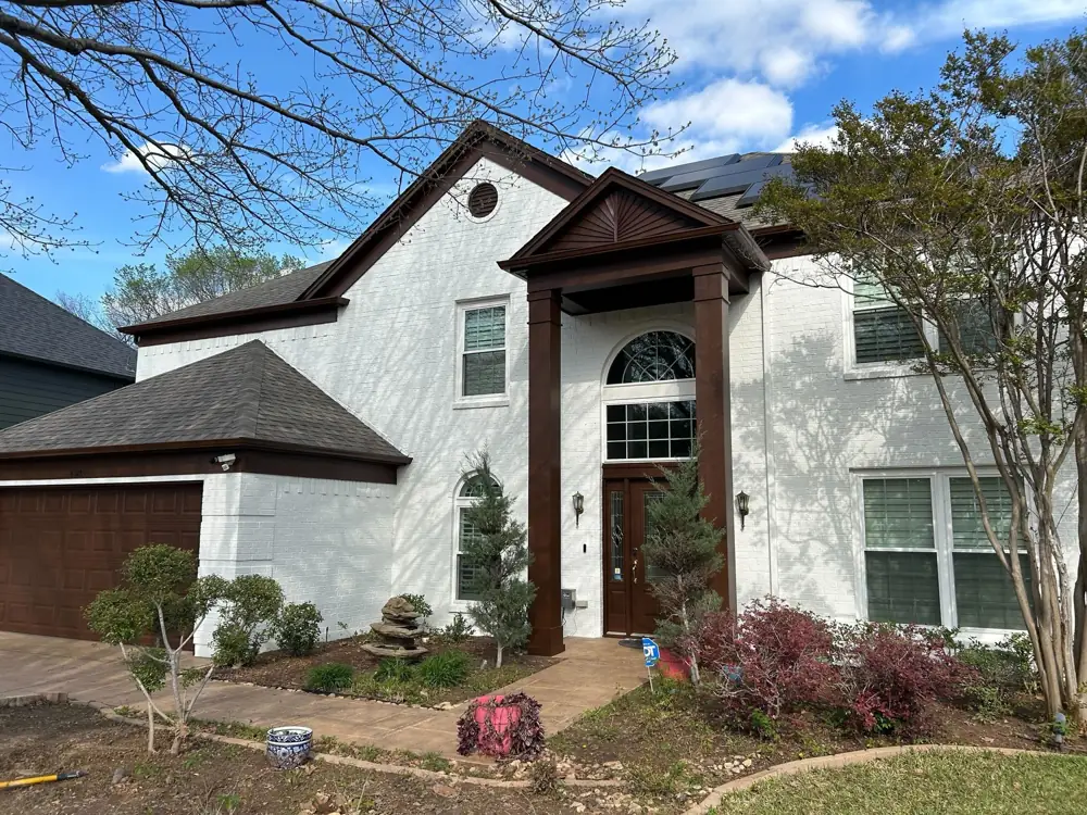 White painted brick house exterior with dark brown trim and garage door in McKinney, TX