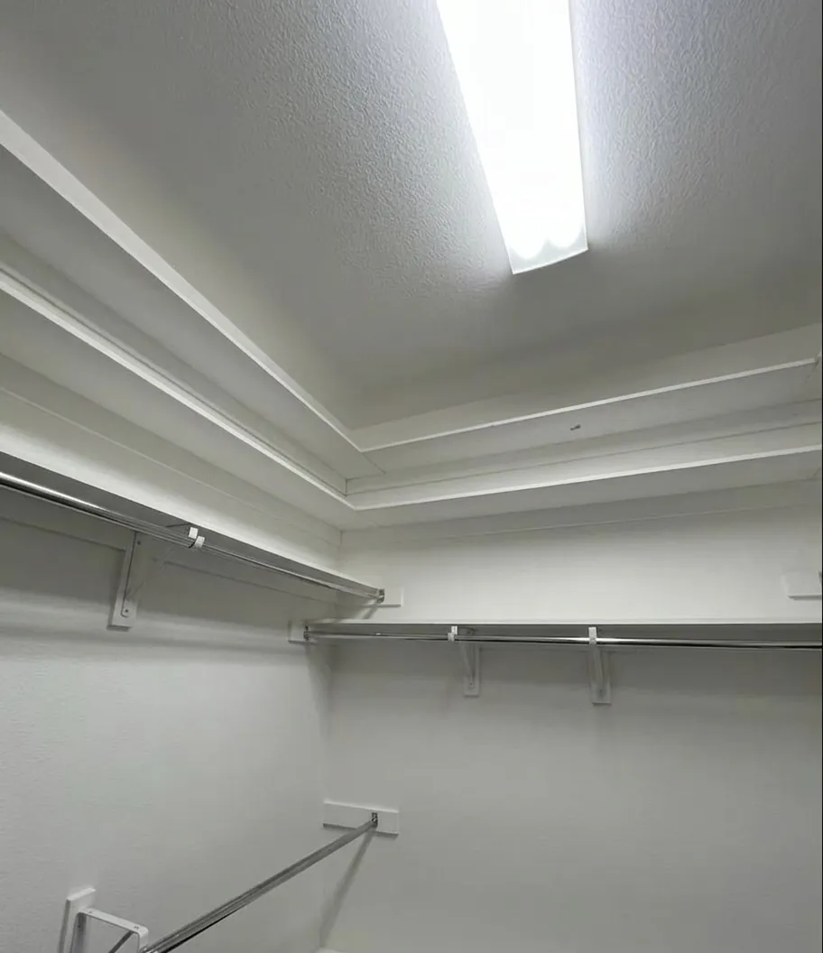Freshly painted walk-in closet with crisp white walls, shelving, and rods in McKinney, TX