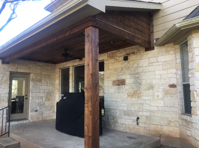 Stained cedar porch cover with tongue-and-groove ceiling on a stone home in McKinney, TX