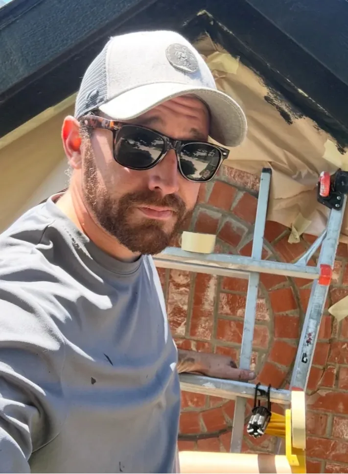 Colin Cooper of Masco Pros on a ladder while painting exterior trim in McKinney, TX