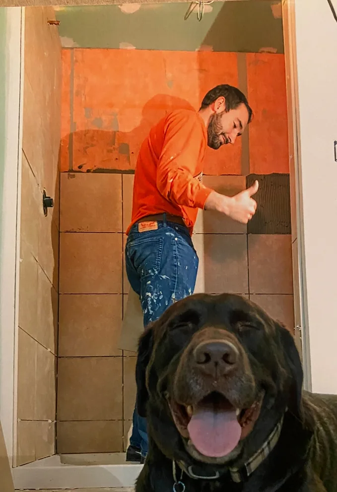 Evan Lemaster of Masco Pros giving a thumbs up while tiling a shower during a remodel